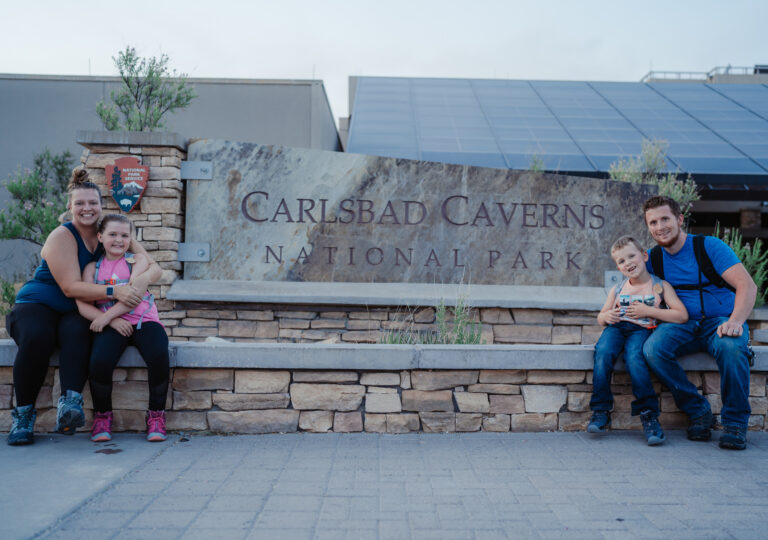 Family Sitting Outside of Carlsbad Cavern Sign